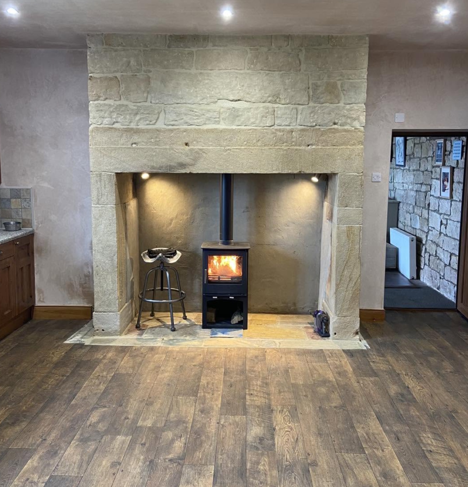 Stone inglenook with recessed lighting above a wood burning stove