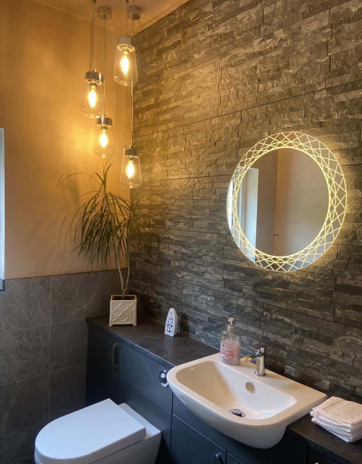 Cloakroom with cluster pendants and a backlit round mirror