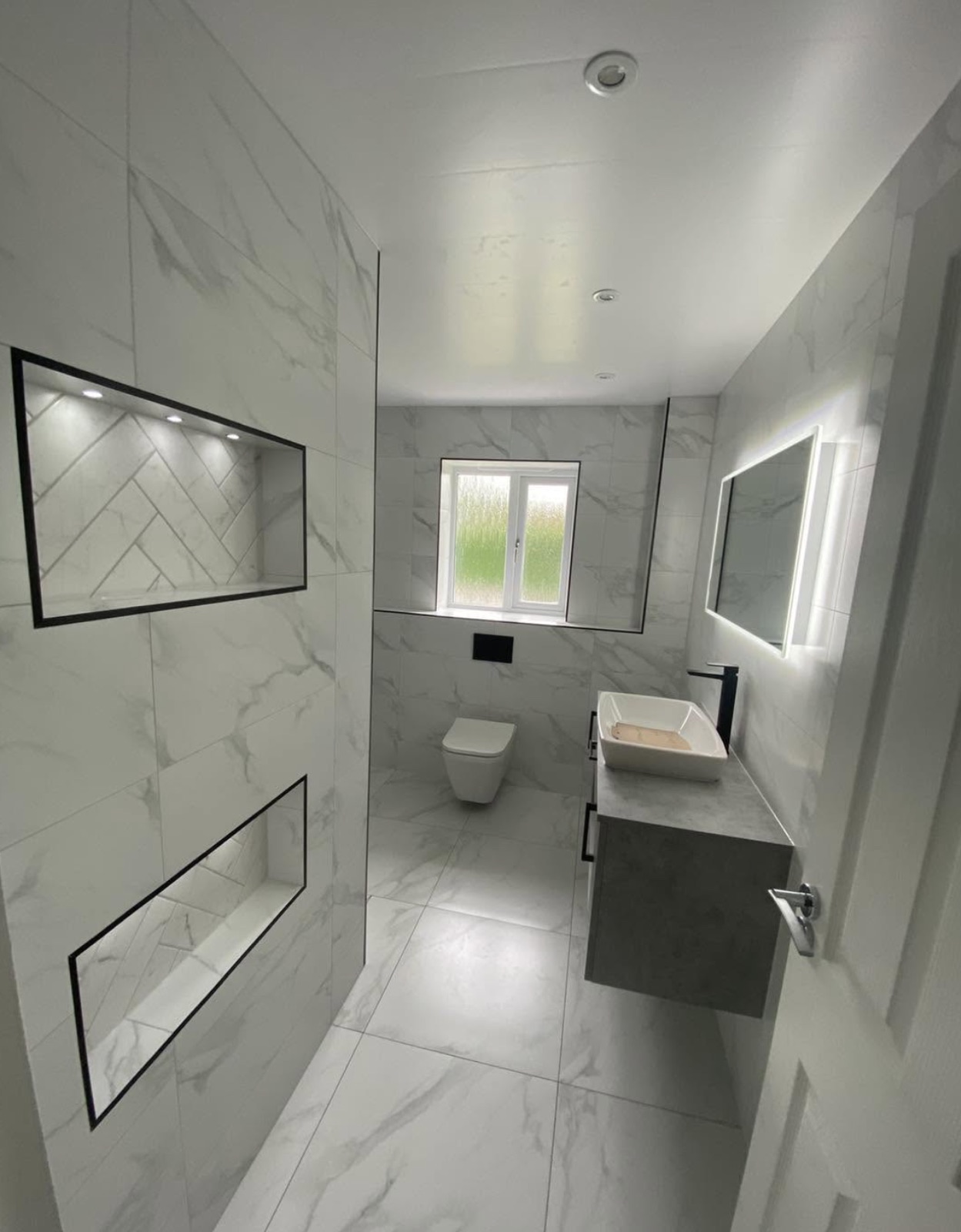 Marble tiled shower room with lit recessed niches